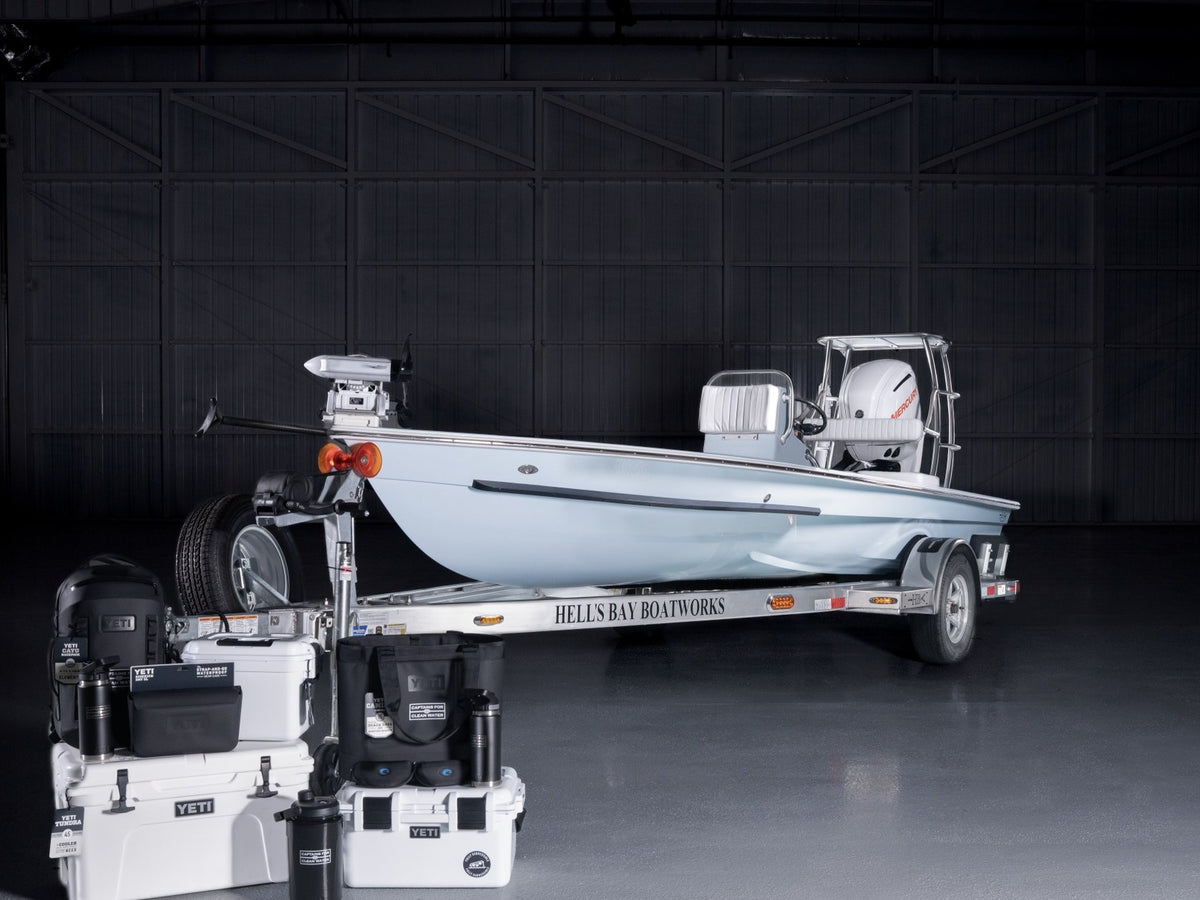 The custom 2026 Hell’s Bay skiff on its trailer in a hangar, with the YETI gear package in front of it
